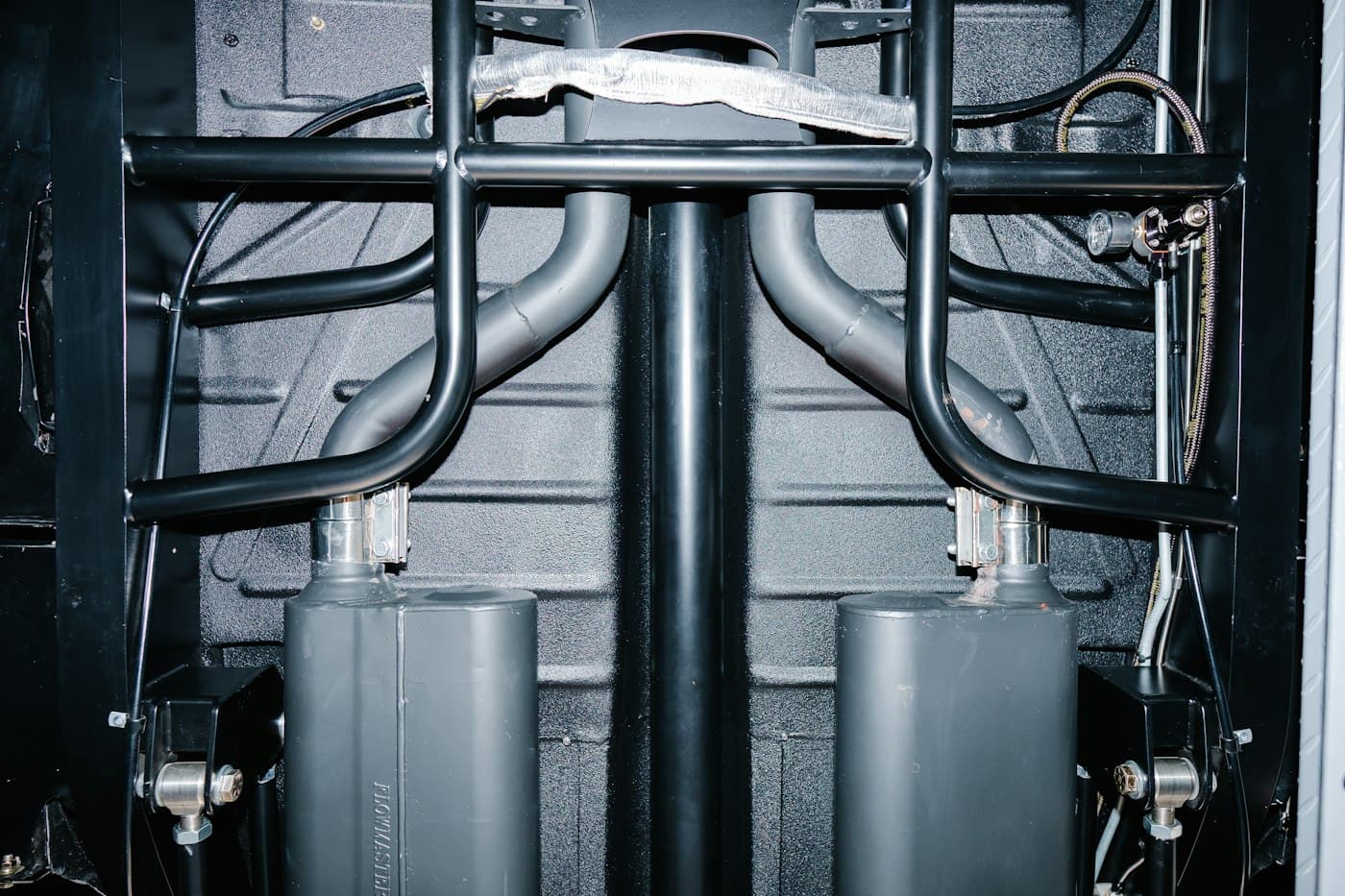 Underside of a vehicle showing mufflers, exhaust pipes, and clamps